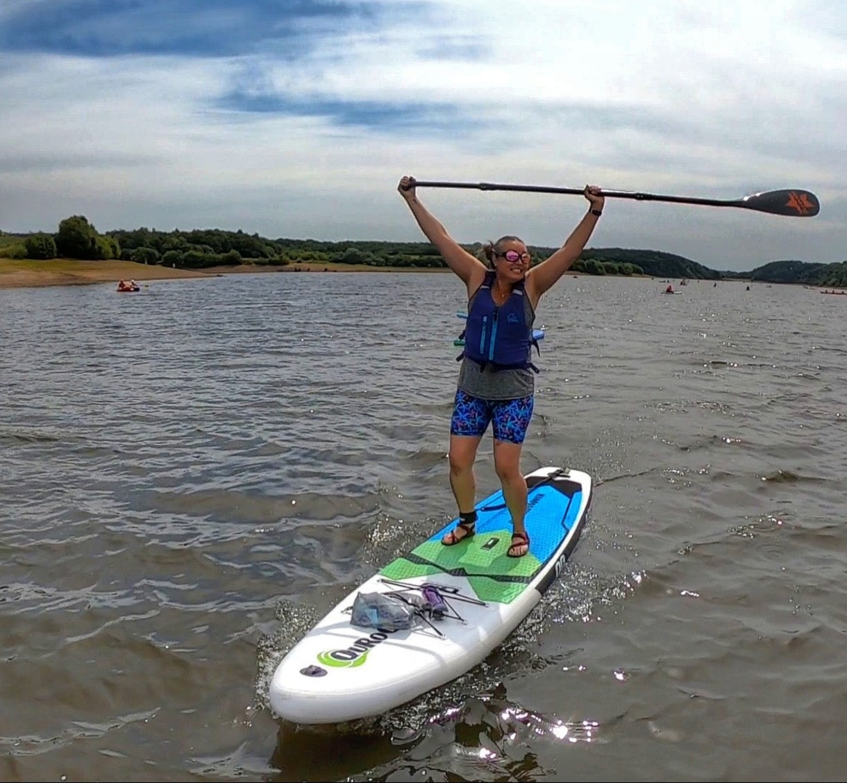 Kirsty on her paddleboard with her paddle held above her head